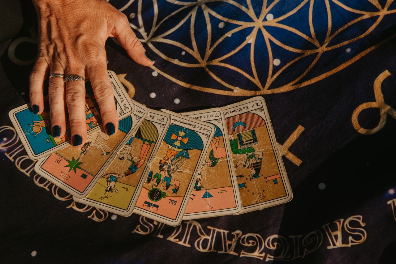 about-02 A hand arranging tarot cards on a star-studded cloth, showcasing divination symbolism.