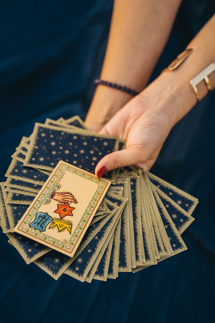 services-01 Close-up of a hand holding tarot cards, symbolizing spirituality and divination.