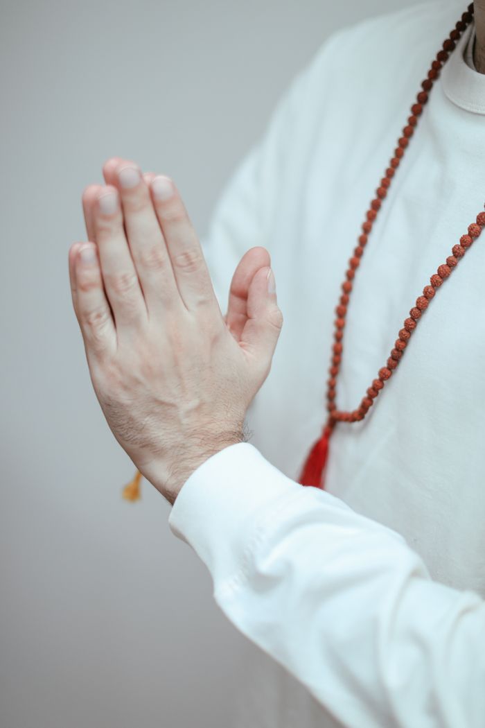 services-06 Close-up of hands in prayer position with rudraksha mala beads, symbolizing spirituality.