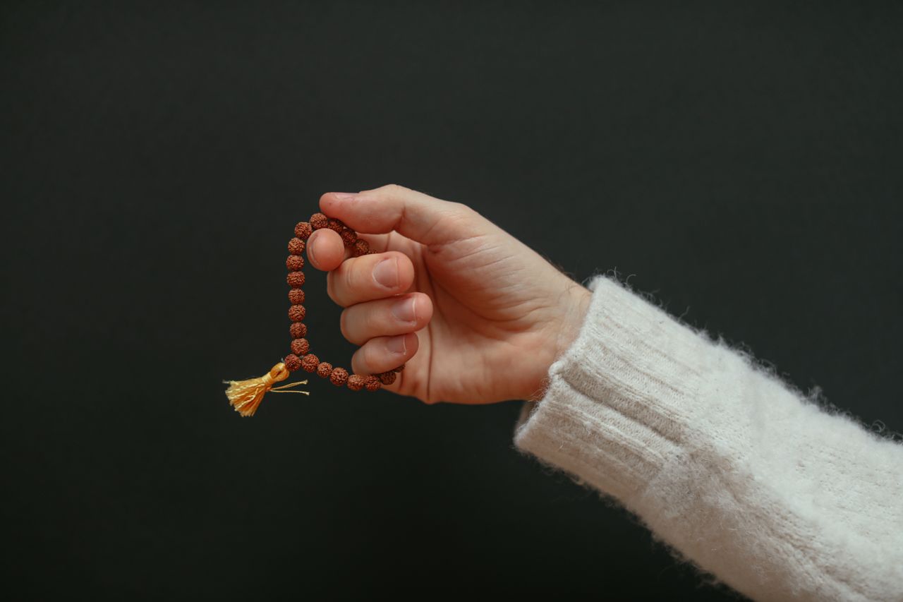 Marriage Delayed? Explore Spiritual & Astrological Guidance A close-up of a hand holding a beaded bracelet against a dark background.