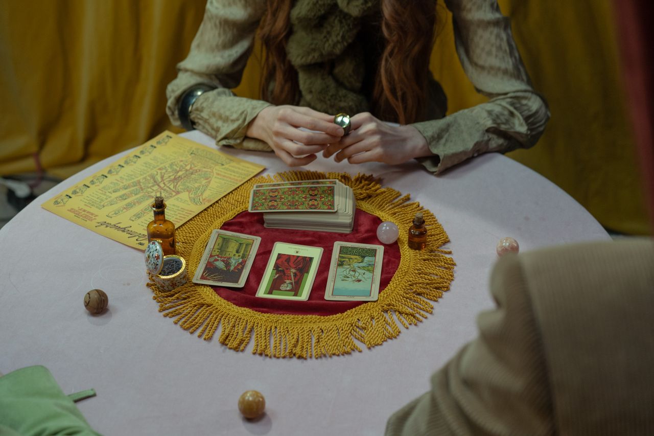 services-01 Mysterious tarot card reading setup with a fortune teller inside a cozy room setting.