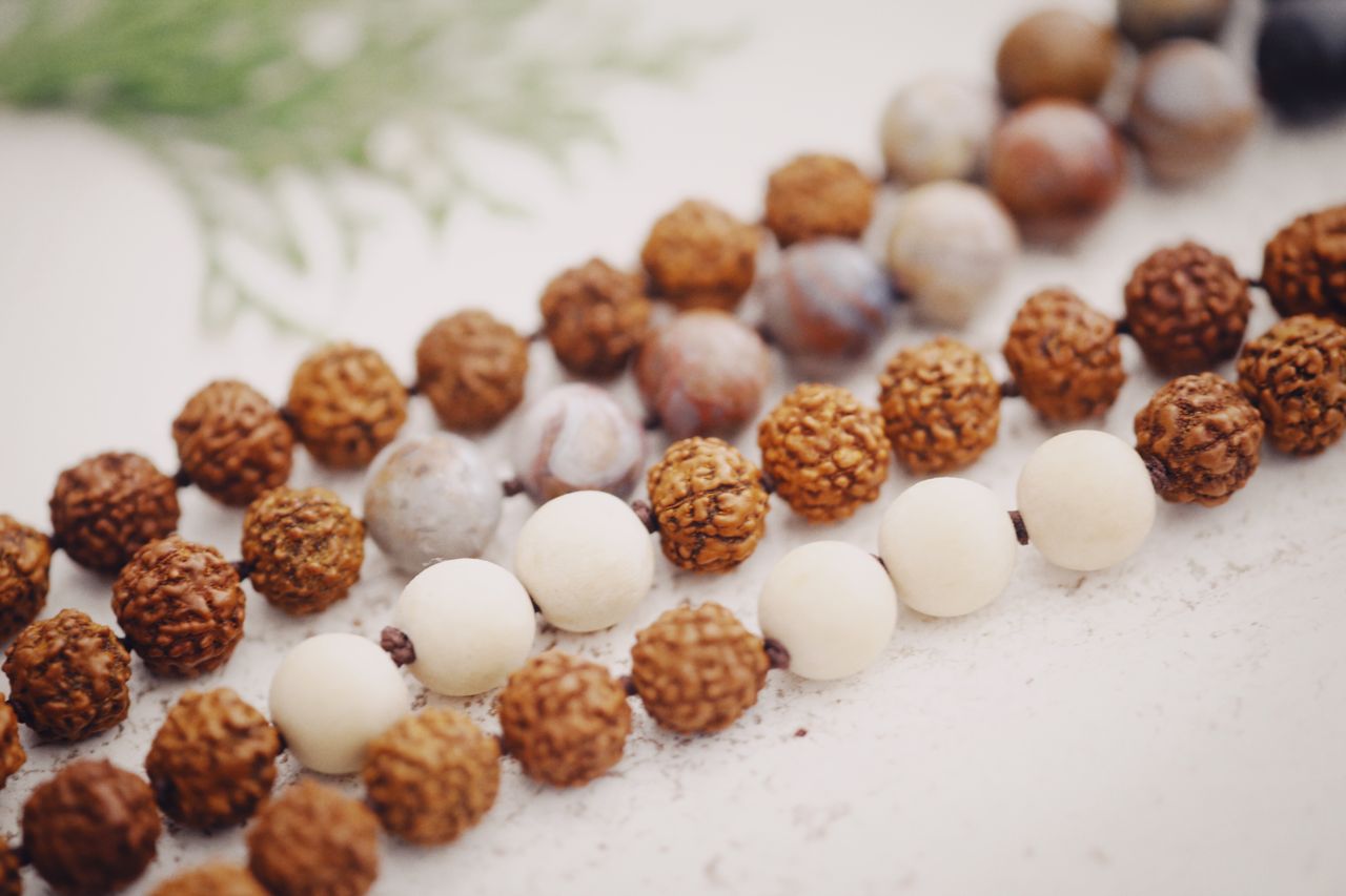 why-choose-us-02 Beautiful close-up of rudraksha and stone beads intricately arranged on a white surface, perfect for meditation themes.